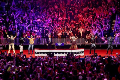 El presidente electo Donald Trump observa a Village People interpretar "YMCA" en el escenario de su mitin de victoria en el Capital One Arena el 19 de enero de 2025 en Washington, DC.