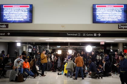 Las pantallas de información en el Aeropuerto Nacional Reagan muestran instrucciones de emergencia mientras los periodistas esperan una conferencia de prensa después de que un avión se estrelló en el río Potomac 