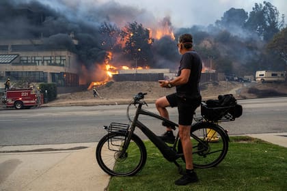 Un hombre observa el avance del fuego sobre las casas