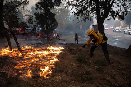 Un bombero intenta detener al fuego para que no llegue a la carretera