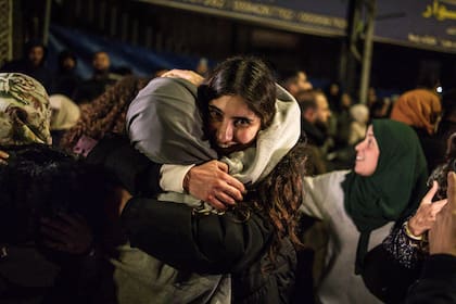 Un prisionero palestino abraza a un familiar a la llegada de unos 90 prisioneros liberados por Israel en la madrugada del 20 de enero de 2025 a la ciudad de Beitunia