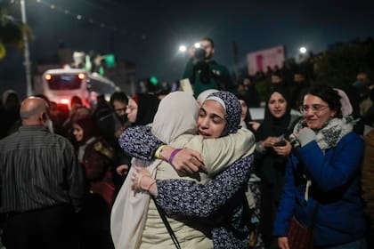 Una prisionera palestina, en el centro a la izquierda, es recibida después de descender de un autobús tras su liberación de una prisión israelí, en la ciudad cisjordana de Beitunia, la madrugada del lunes 20 de enero de 2025. (Foto AP/Leo Correa)