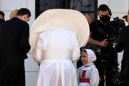 El papa Francisco es recibido por una niña con traje tradicional durante una ceremonia de bienvenida en el Palacio Presidencial en Bratislava, Eslovaquia, el 13 de septiembre de 2021