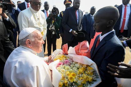 El papa Francisco recibe un ramo de flores de un niño cuando llega al Aeropuerto Internacional de Juba, en Sudán del Sur, el 3 de febrero de 2023